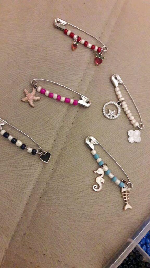 Safety pins with various colorful beads and some charms on them