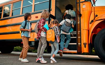 Kids lined up to get on a yellow school bus