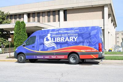 Blue and red van sitting in a parking lot outside a two story building