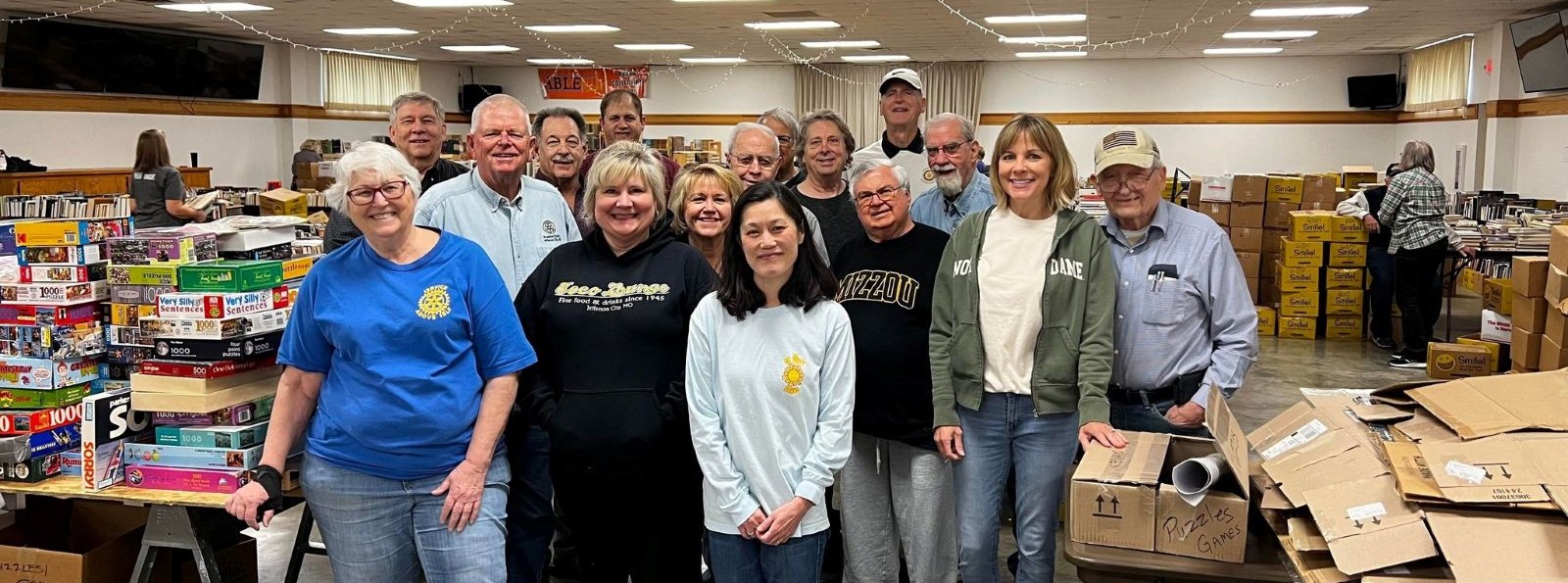 Group photo of 16 smiling volunteers at the book sale setup event